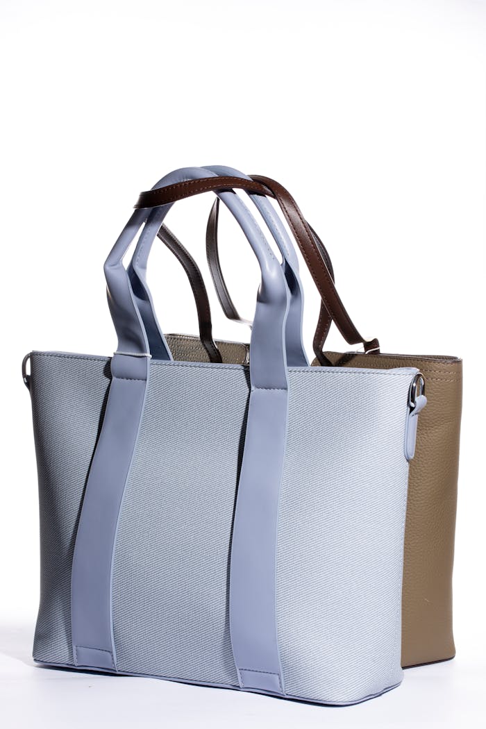 Two elegant tote bags in blue and tan displayed on a white backdrop showcasing modern style.